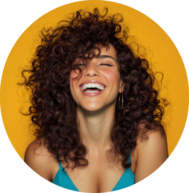 Woman with voluminous curly dark hair laughing with eyes closed against a warm orange background